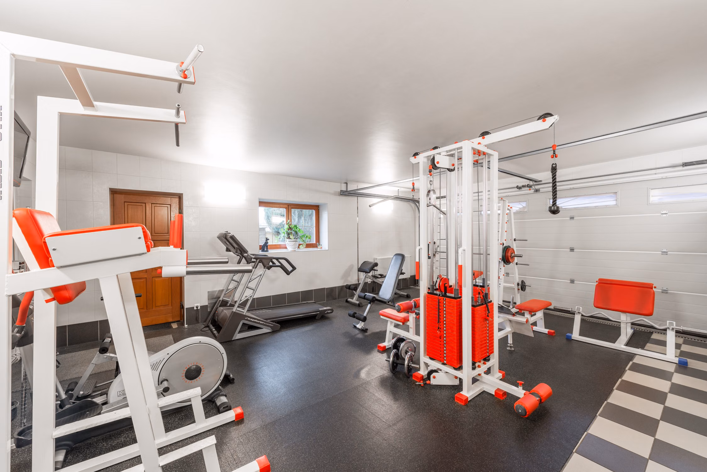 Bright basement home gym with treadmills, benches, and weights
